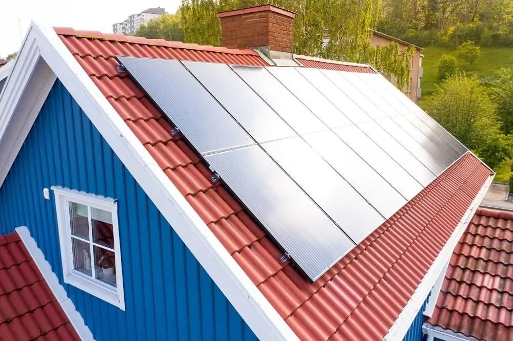 blått hus med solceller på rött tegeltak