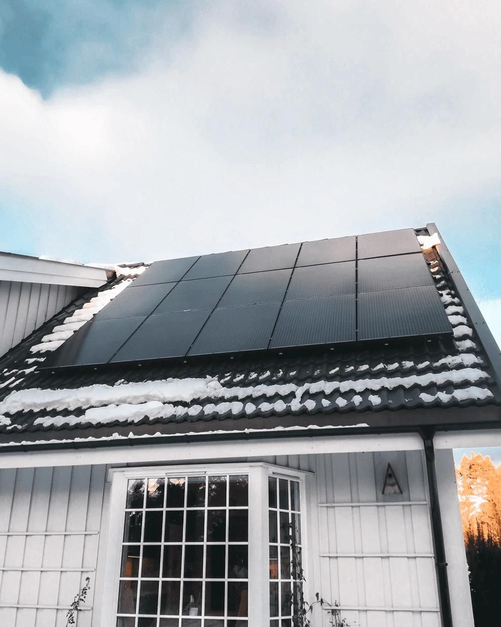 solpaneler på tak som har snö på sig