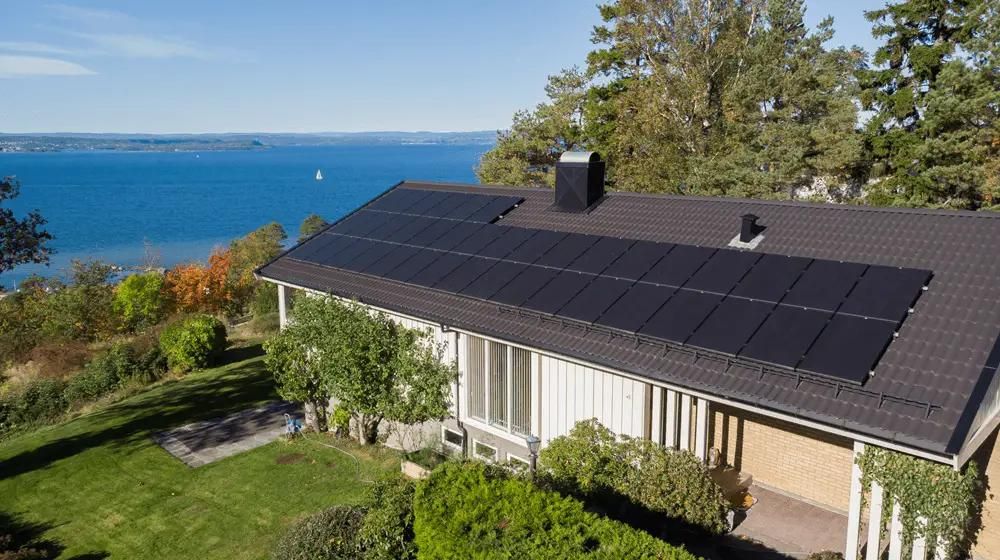 hus med solpaneler installerade på taket och utsikt över blått hav
